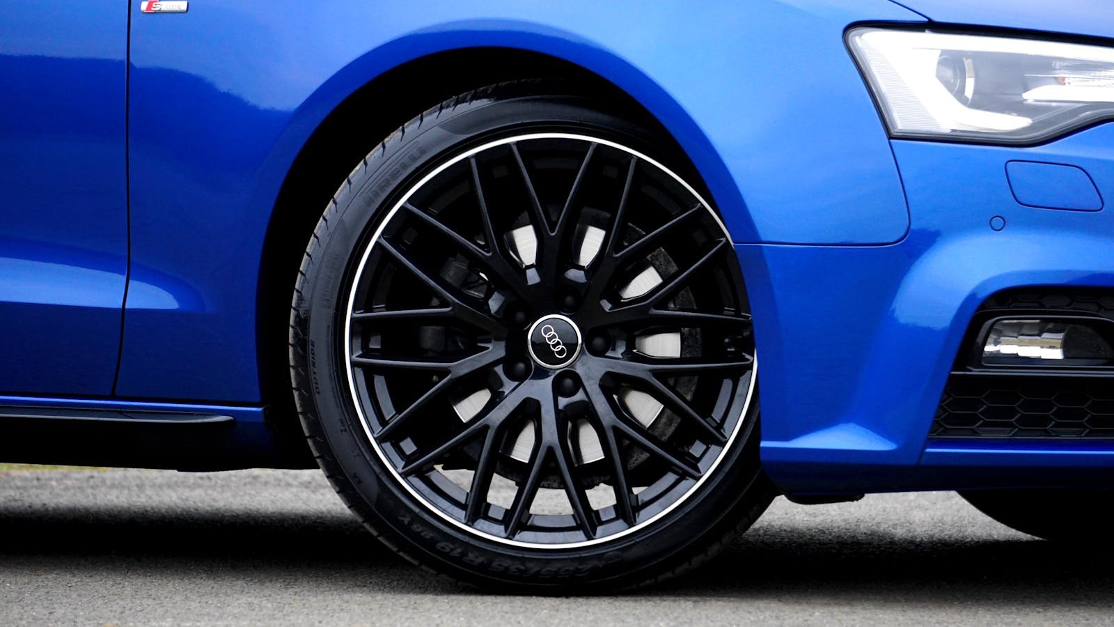 Detailed close-up of a blue Audi car rim and tire, showcasing design and style.